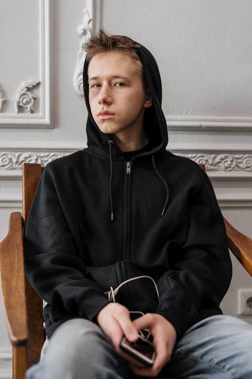 man in black hoodie sitting on brown wooden chair