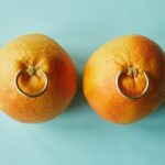 ripe tangerines with golden earrings against blue background