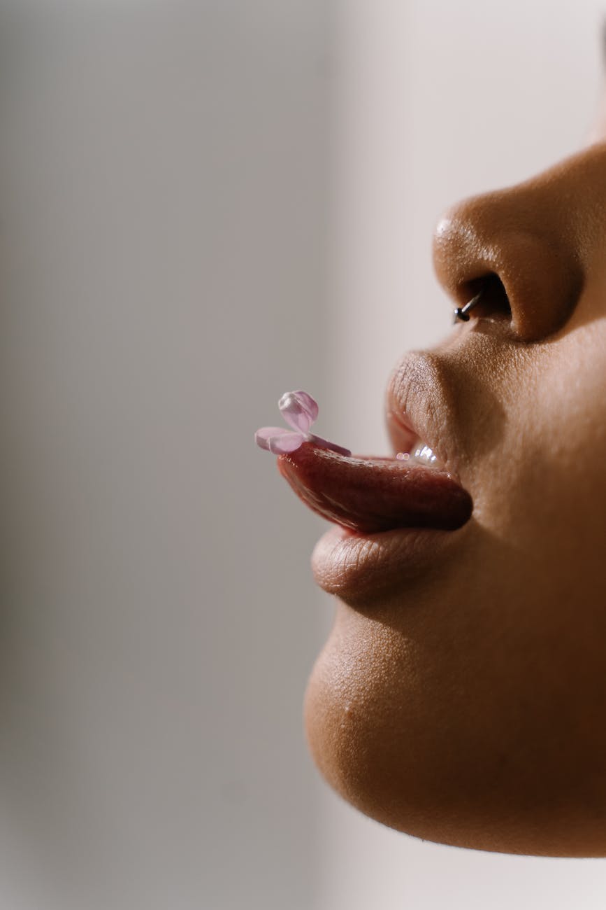 a close up shot of a pink flower on a woman s tongue